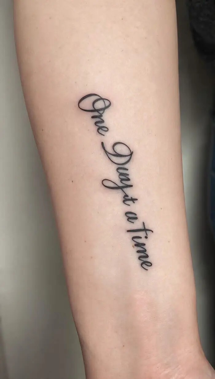 "One Day at a Time" Script Tattoo Design on Forearm 