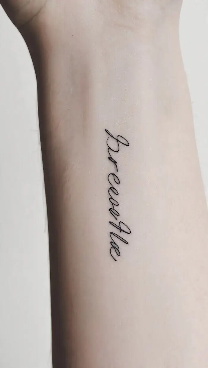 Minimalist “Breathe” Script Tattoo on Inner Forearm