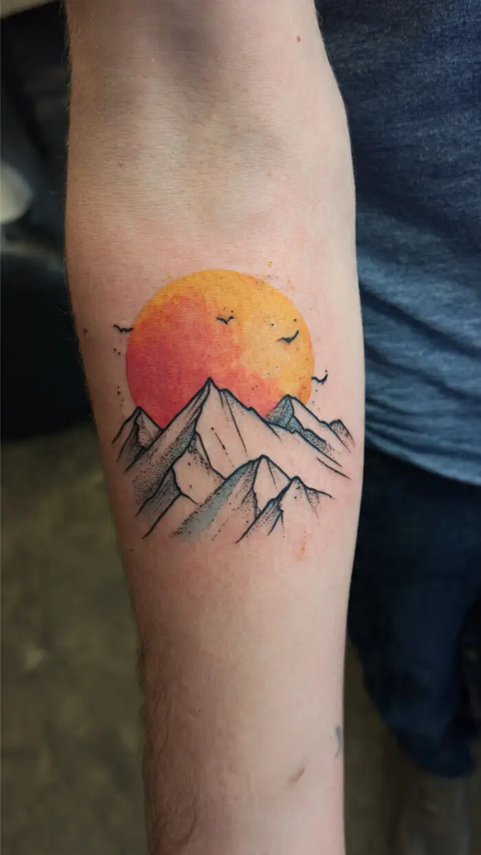 Elegant Watercolor Sunset Mountain Tattoo on Forearm