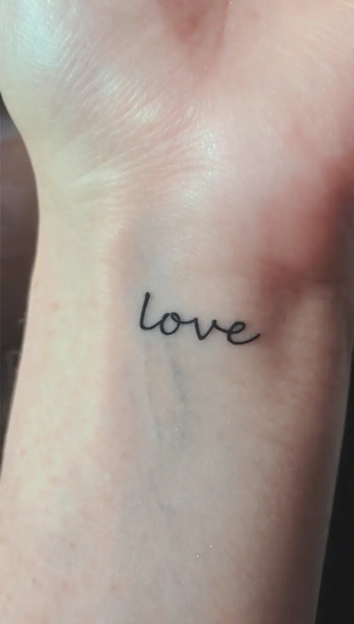 Minimalist "Love" Wrist Tattoo in Elegant Script Design