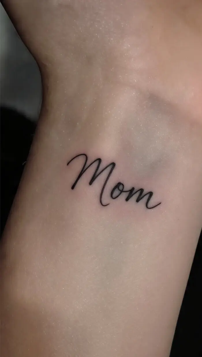 Minimalist “Mom” Script Tattoo on Wrist – Elegant Handwritten Name Tattoo Design