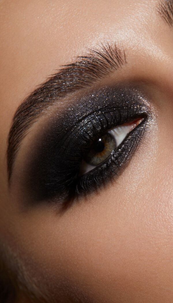 Close-up of dramatic black smokey eye makeup with bold lashes and defined brows.