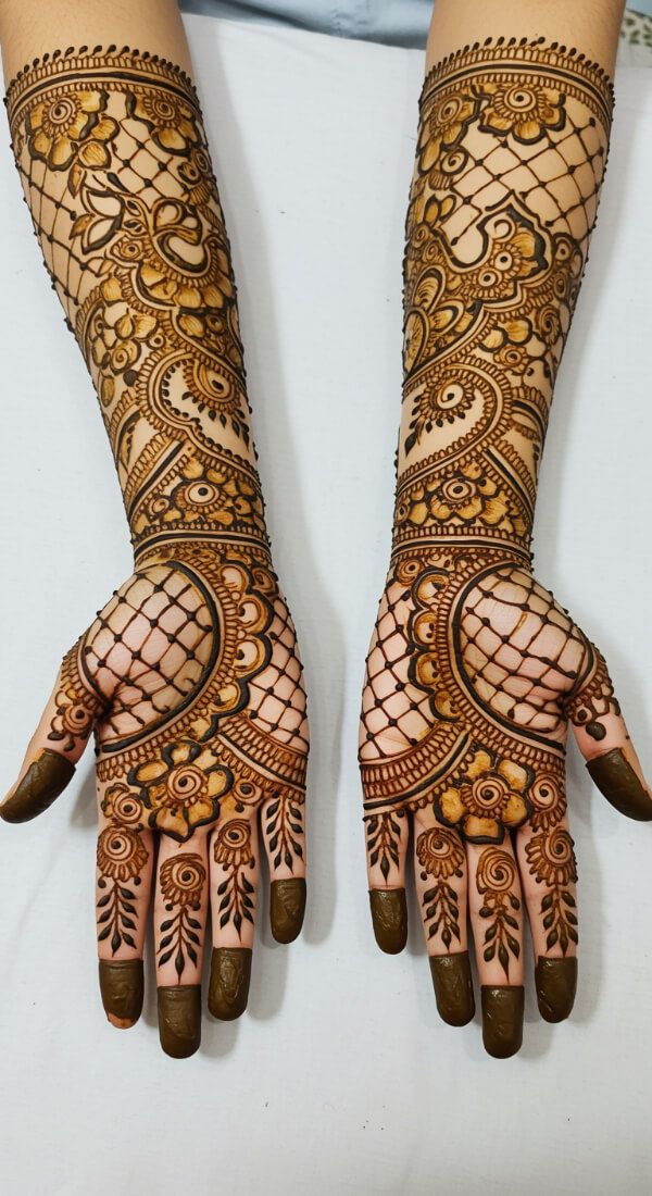 Bridal mehndi design with net pattern, paisley curves, and floral motifs.